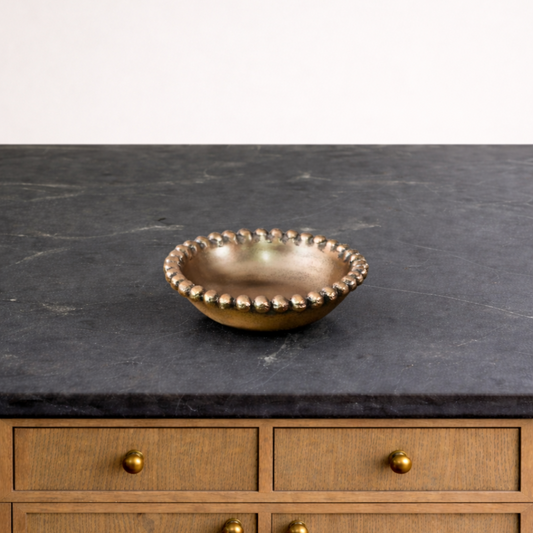 Bronze bowl on a dark countertop with wooden cabinets in the background