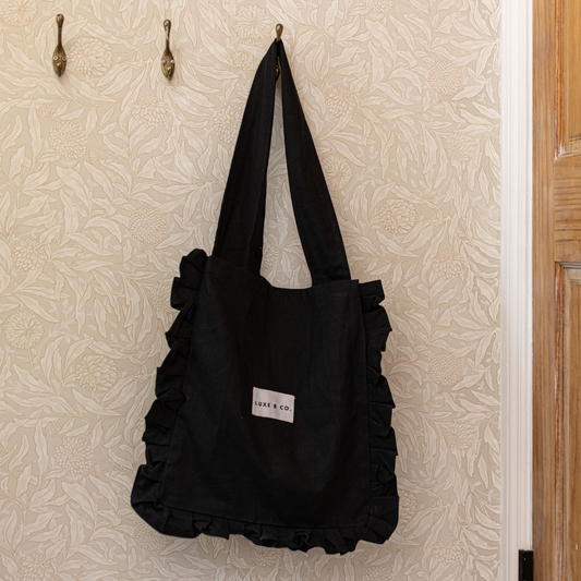 Black ruffle tote bag by Luxe B Co featuring soft fabric, stylish ruffle details, and spacious interior for everyday use.