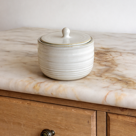 White ceramic jar with lid on a marble countertop