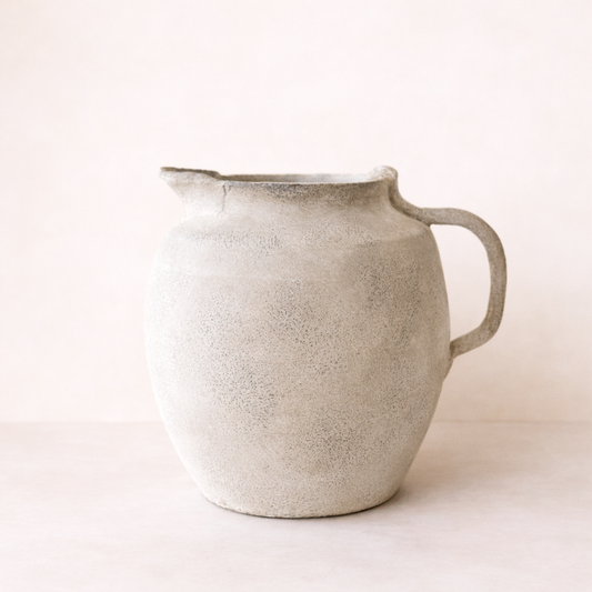 cream pitcher vase with a textured surface on a light background