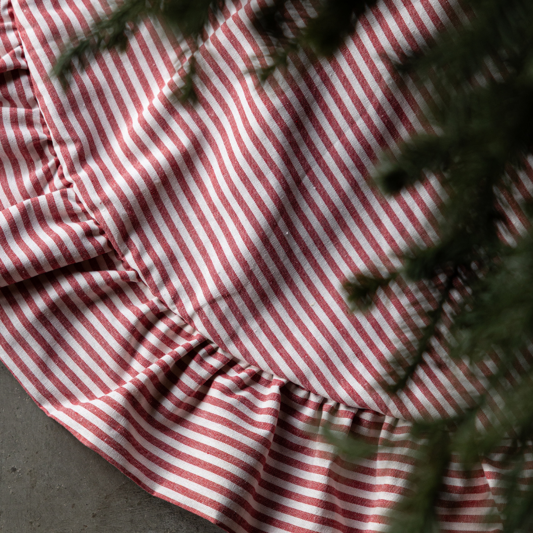 Red Stripe Ruffle Tree Skirt by Luxe B Co., featuring red and white striped fabric with ruffle trim around a festive tree skirt.