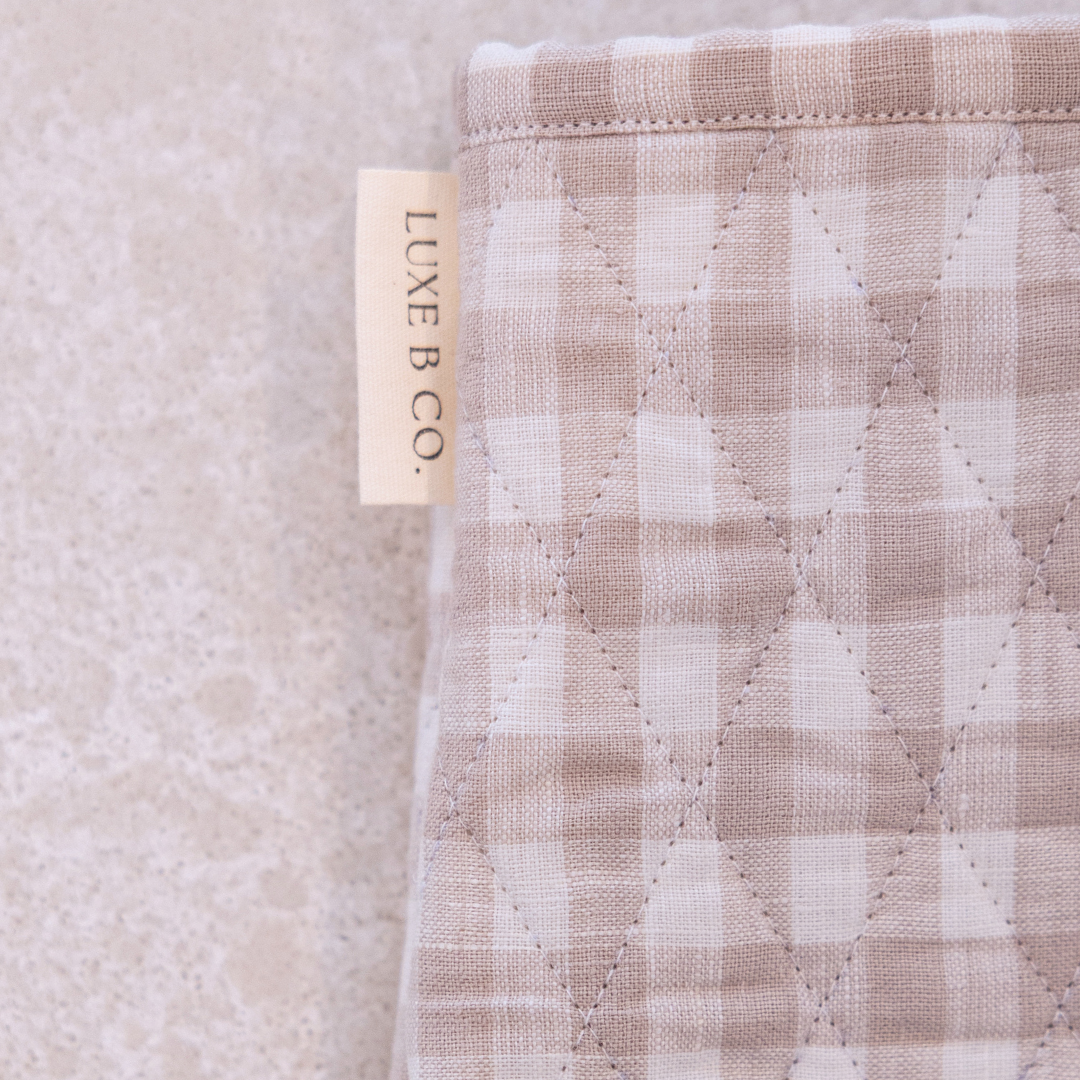 Beige gingham linen oven mitt by Luxe B Co. with quilted design, heat-resistant padding, and comfortable hanging loop.