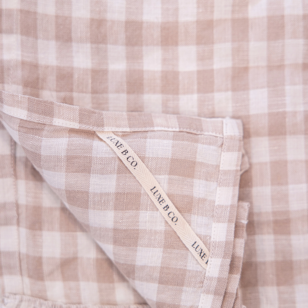 Beige gingham linen dish towel with ruffle detail from Luxe B Co, perfect for kitchen decor and drying dishes.