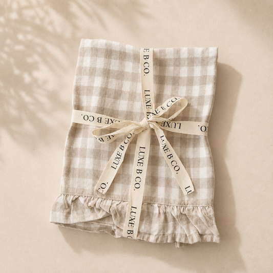 Beige gingham linen dish towel with ruffle edge by Luxe B Co, ideal for kitchen decor and drying dishes.