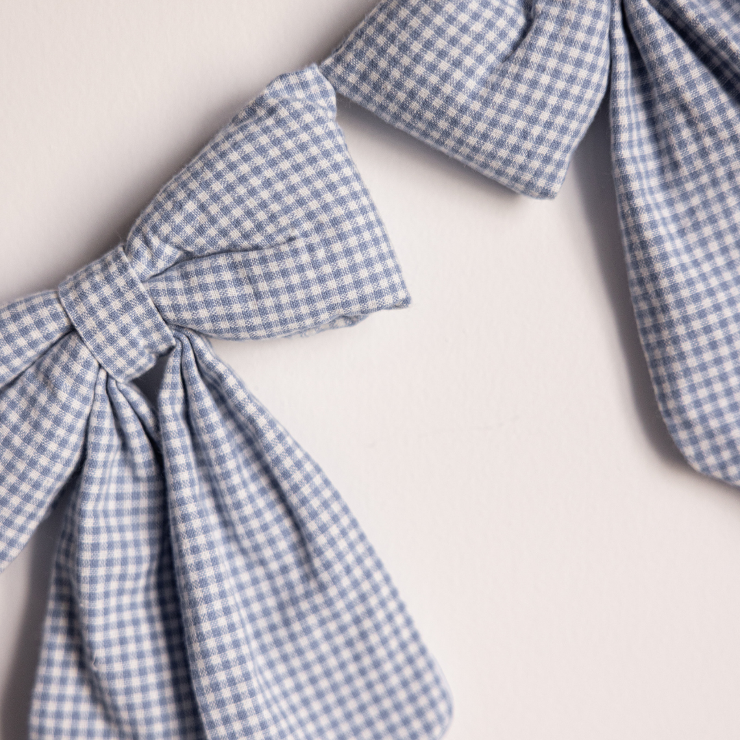 Blue mini gingham fabric bow garland with small bows, decorative accessory by Luxe B Co for gatherings or home decor.