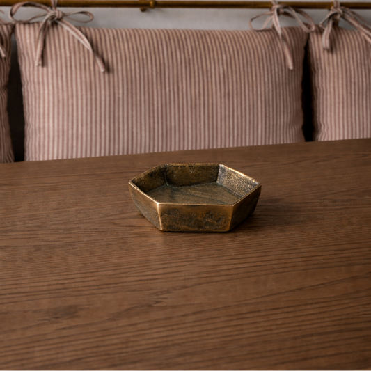 Bronze hexagonal dish on a wooden surface with a neutral background
