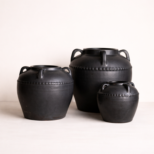 Three black leather-bound containers on a white background