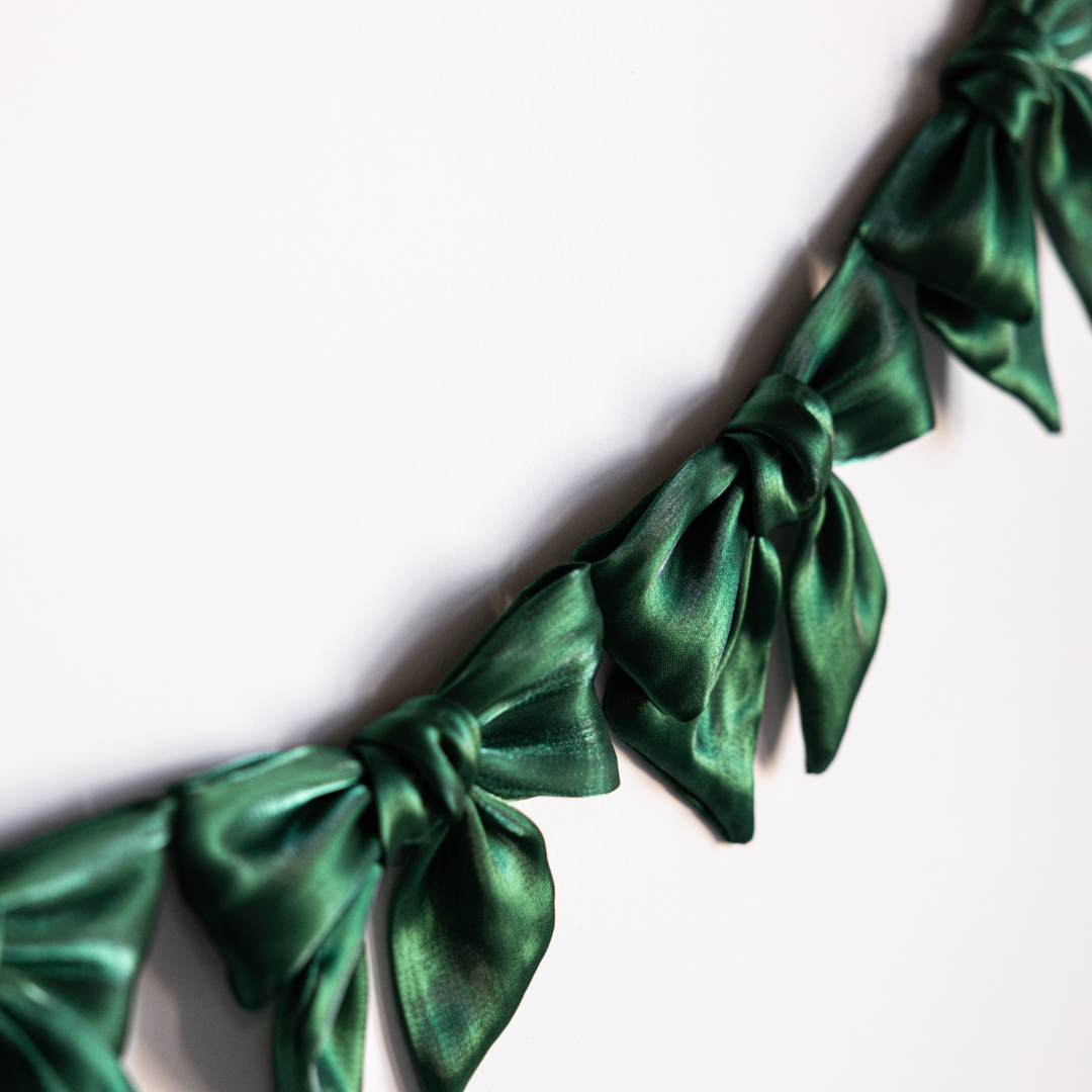 Emerald green gauze bow garland with multiple soft fabric bows, perfect for decorative celebrations and events.