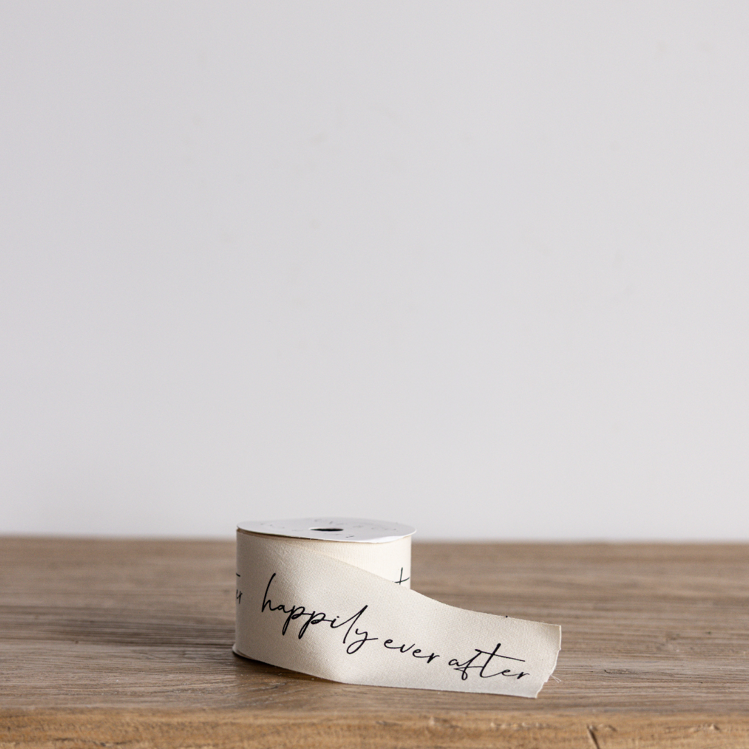 Elegant "Happily Ever After" cursive writing ribbon by Luxe B Co Wholesale, featuring intricate script on satin material.