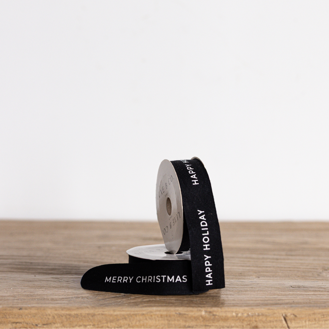 Black holiday ribbon by Luxe B Co with festive "Happy Holiday" design, perfect for Christmas gift wrapping and decorations.
