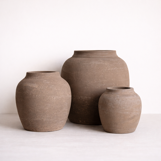 Three brown ceramic jars of different sizes on a white background