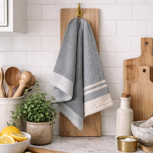 Kitchen counter with a towel hanging on a wooden board, cutting boards, and kitchen utensils.