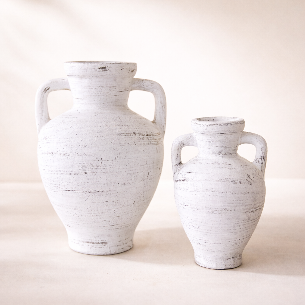Two white ceramic vases with handles on a light beige background