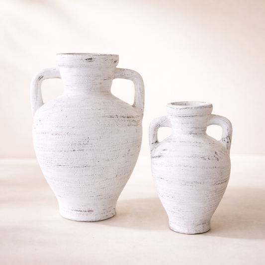 Two white ceramic vases with handles on a light beige background