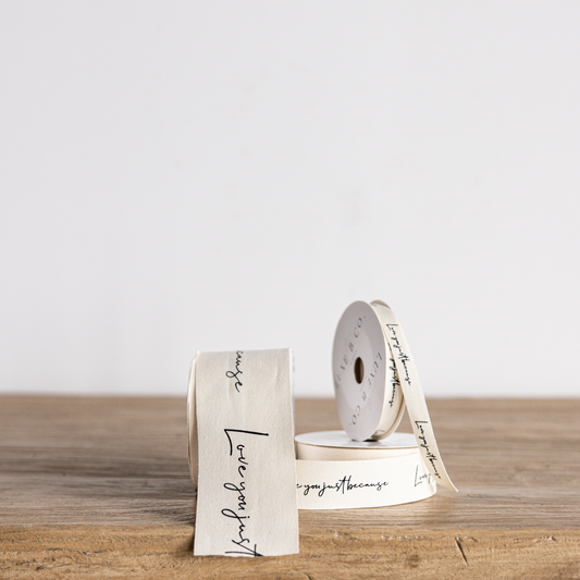 Cursive writing ribbon with "Love You Just Because" phrase, white ribbon by Luxe B Co Wholesale, ideal for gift wrapping and crafts.
