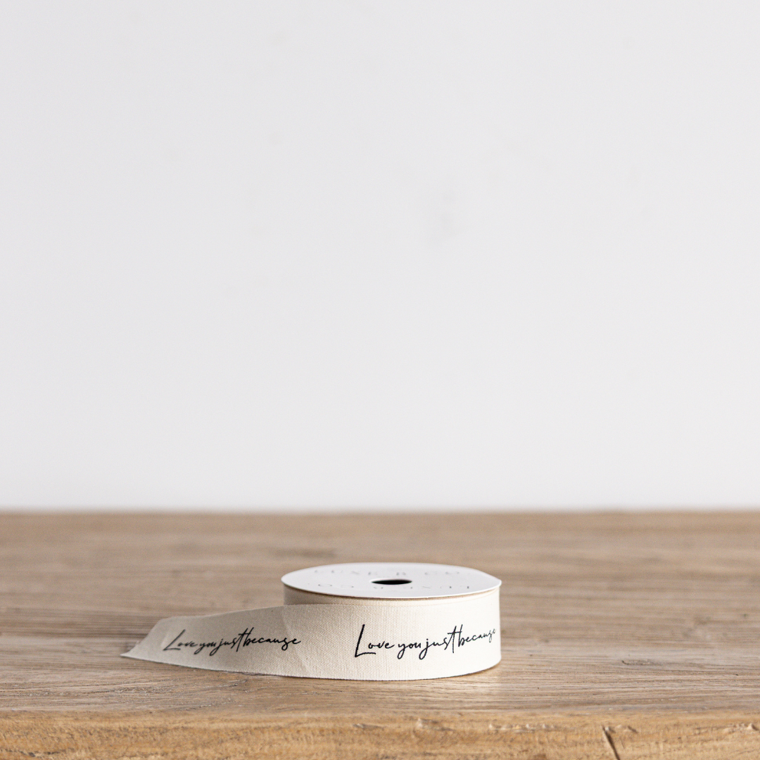 Cursive writing ribbon with "Love You Just Because" text in elegant script, white ribbon by Luxe B Co Wholesale.