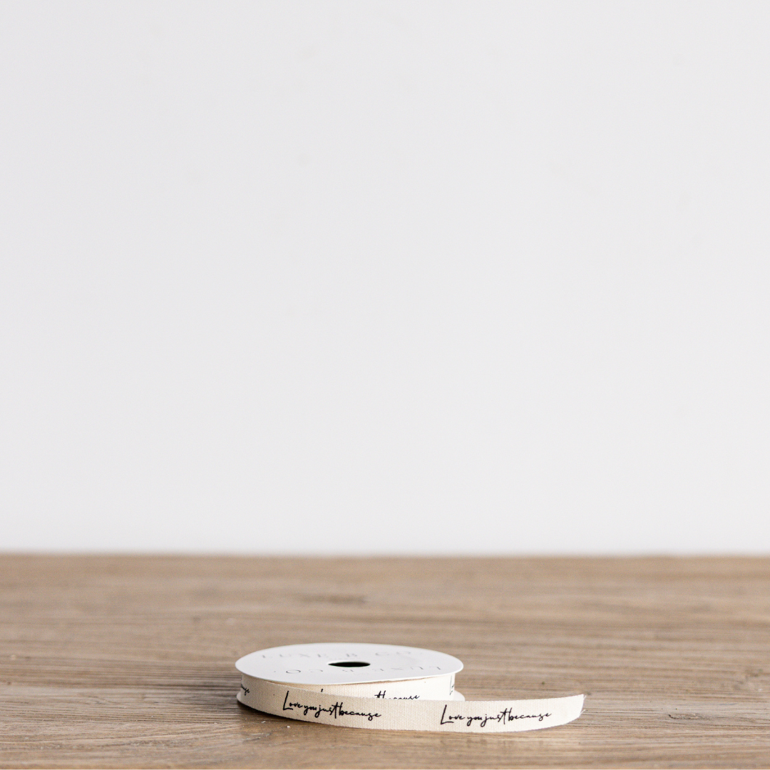 Cursive writing ribbon with "Love You Just Because" message from Luxe B Co Wholesale, decorative fabric ribbon for gift wrapping.