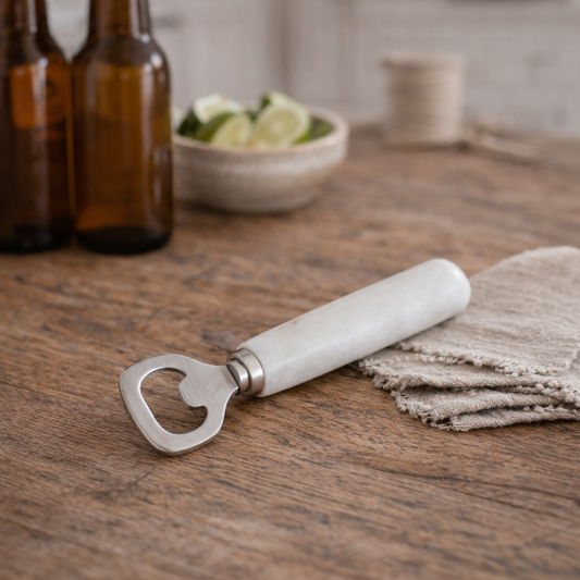 Bottle opener with marble handle on a wooden table with bottles and lime in the background