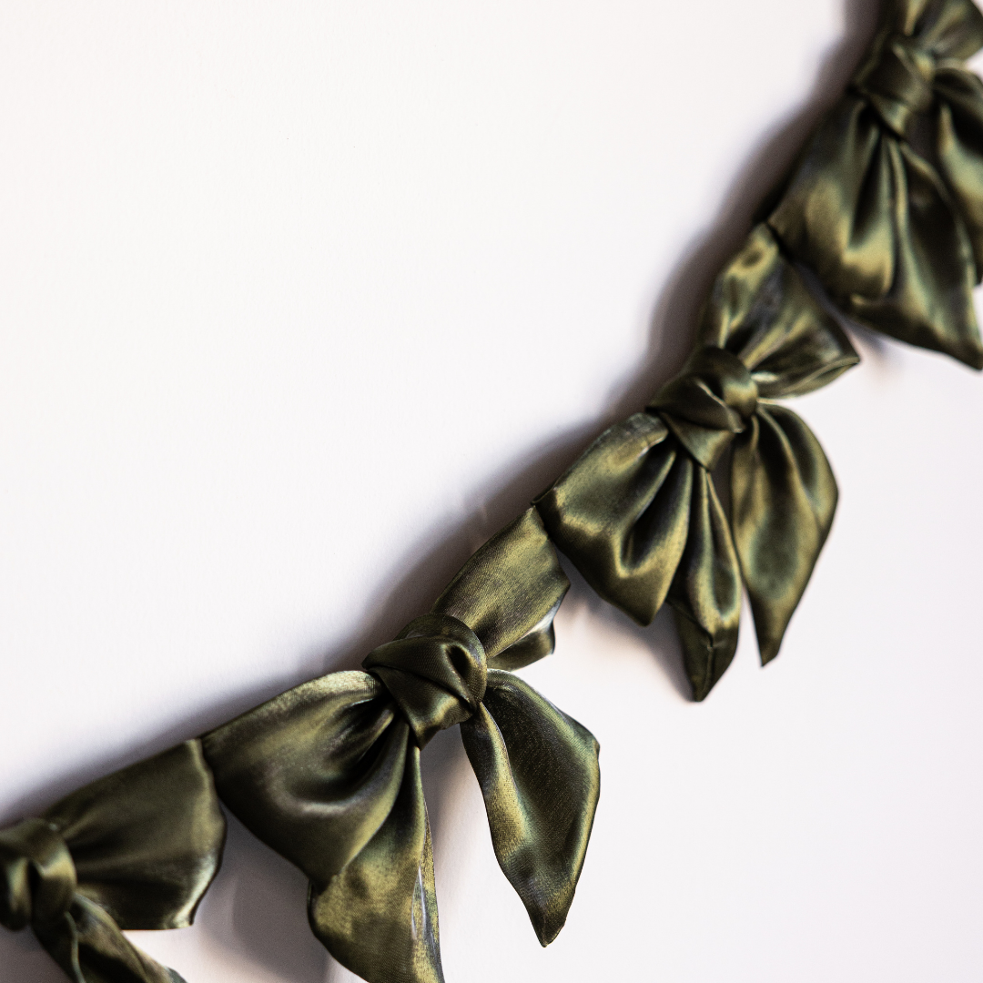 Olive green gauze bow garland by Luxe B Co, featuring soft fabric bows arranged in a decorative garland for celebrations.