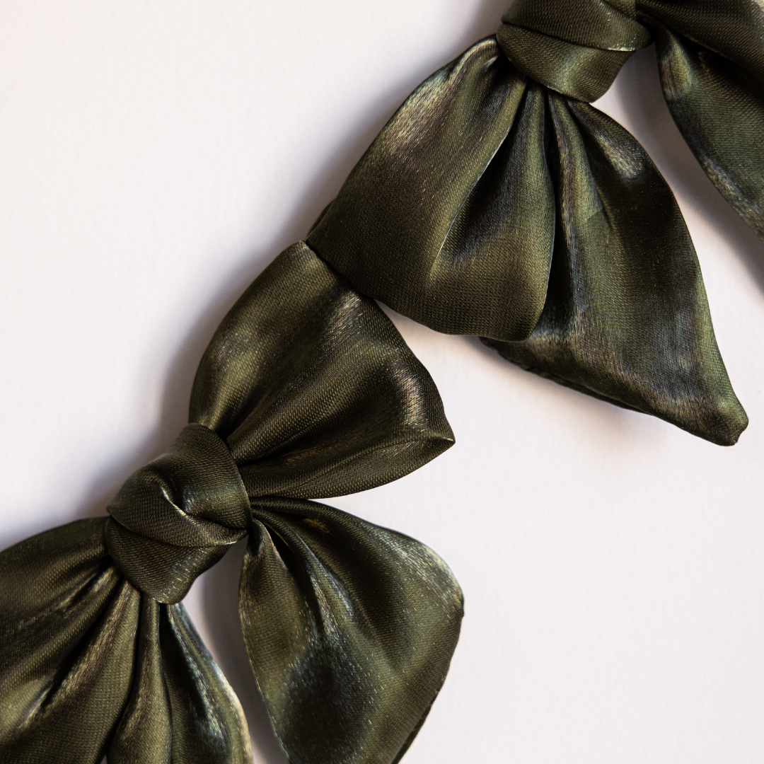 Olive green gauze bow garland by Luxe B Co featuring soft, airy fabric bows for decorative occasions.