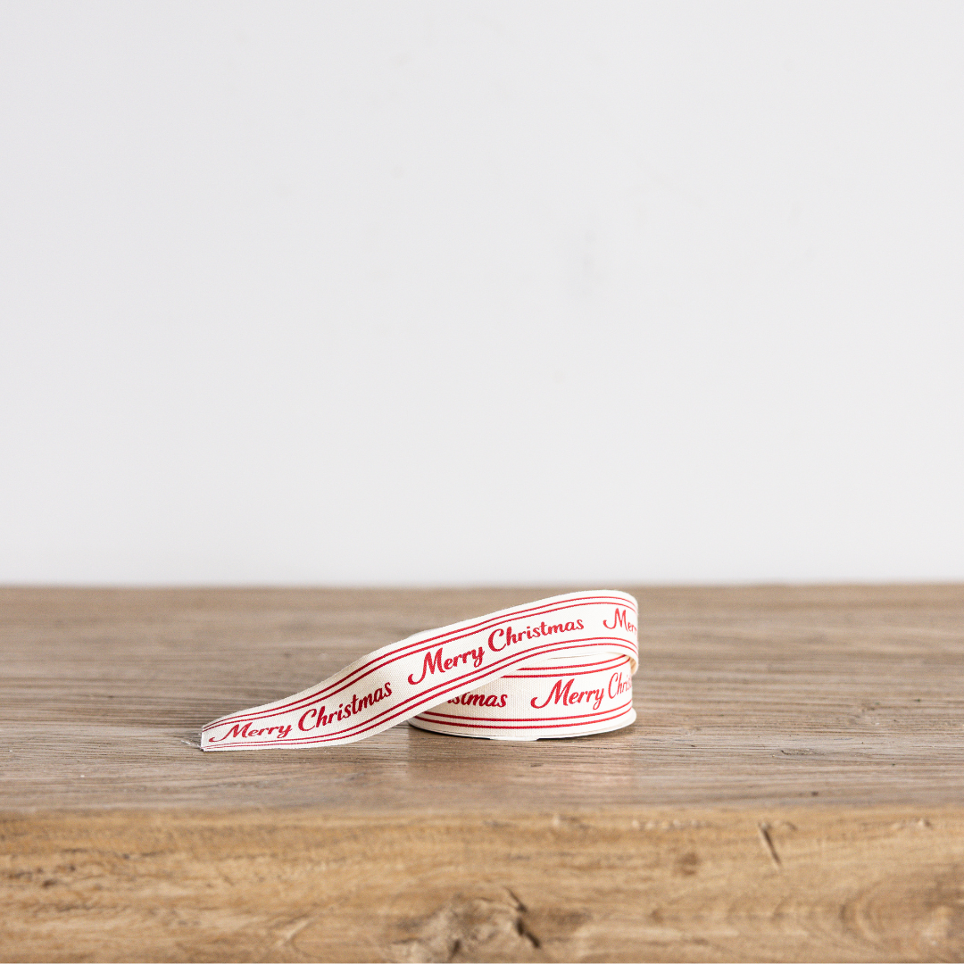 Red cursive Merry Christmas ribbon by Luxe B Co Wholesale, featuring festive holiday lettering on satin fabric.