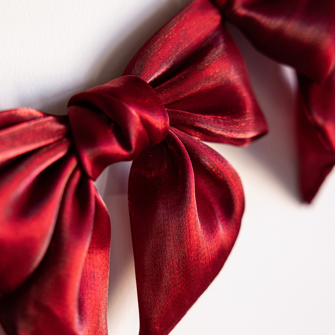 Red gauze bow garland by Luxe B Co featuring soft, airy fabric bows for festive or decorative occasions.