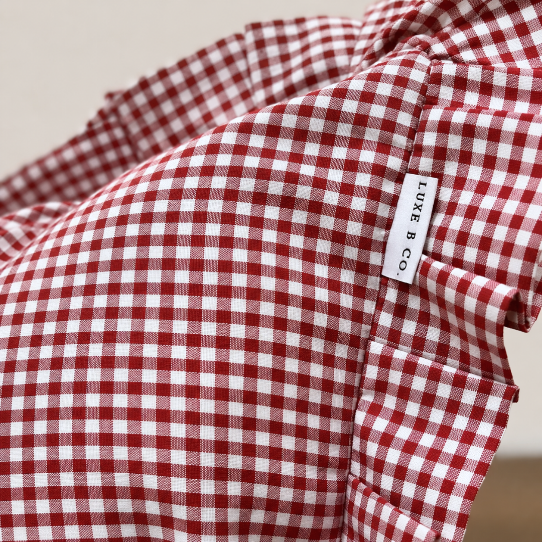 Red gingham ruffle bolster pillow cover by Luxe B Co, featuring a soft fabric with decorative ruffled edges.