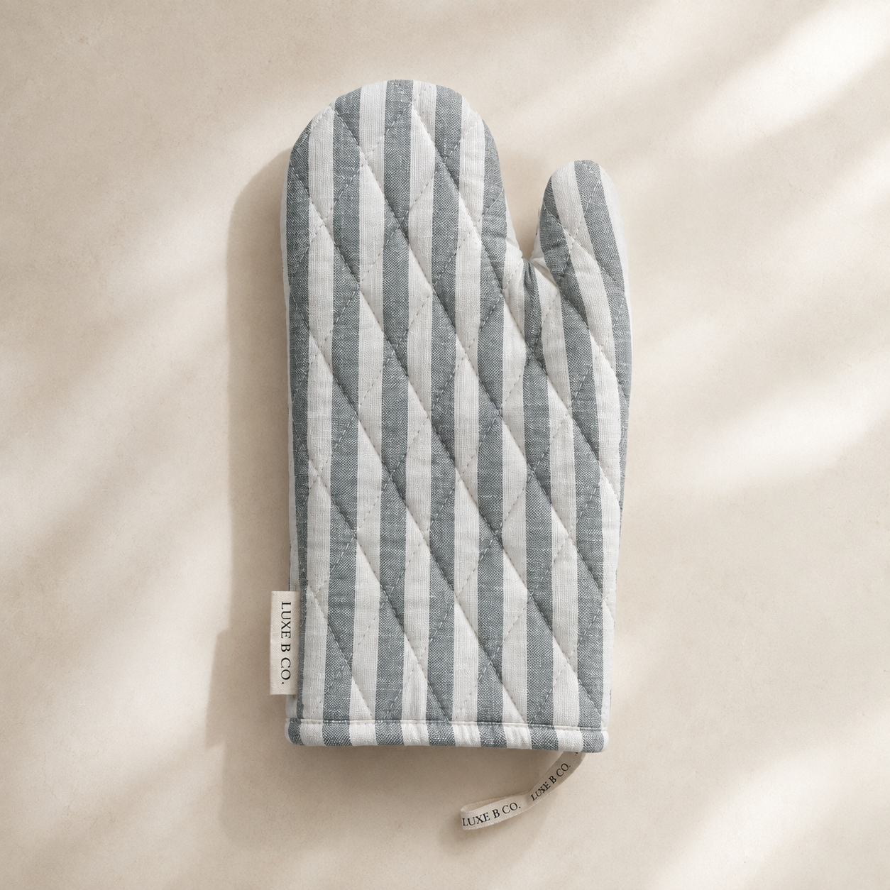 Soft green striped linen oven mitt by Luxe B Co., featuring a comfortable, heat-resistant design with a stylish striped pattern.