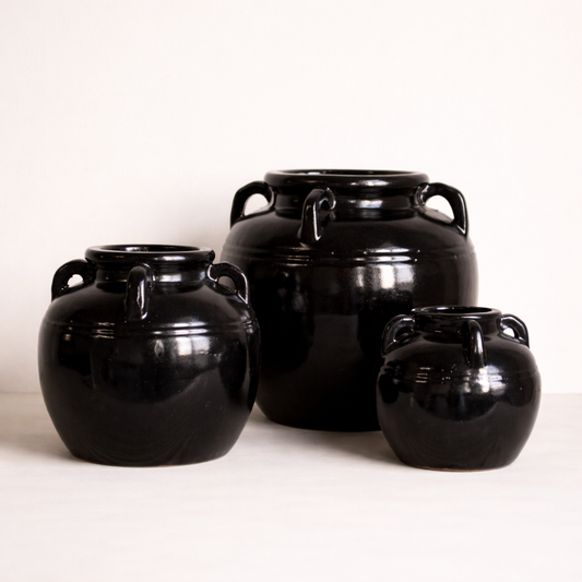 Three black ceramic jars of varying sizes on a white background
