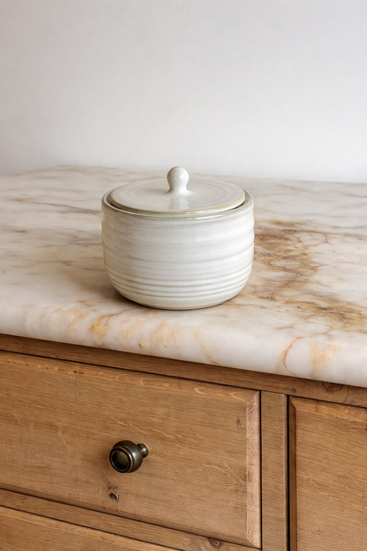 White ceramic jar with lid on a marble countertop
