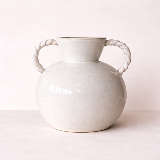White ceramic vase with rope handles on a light pink background